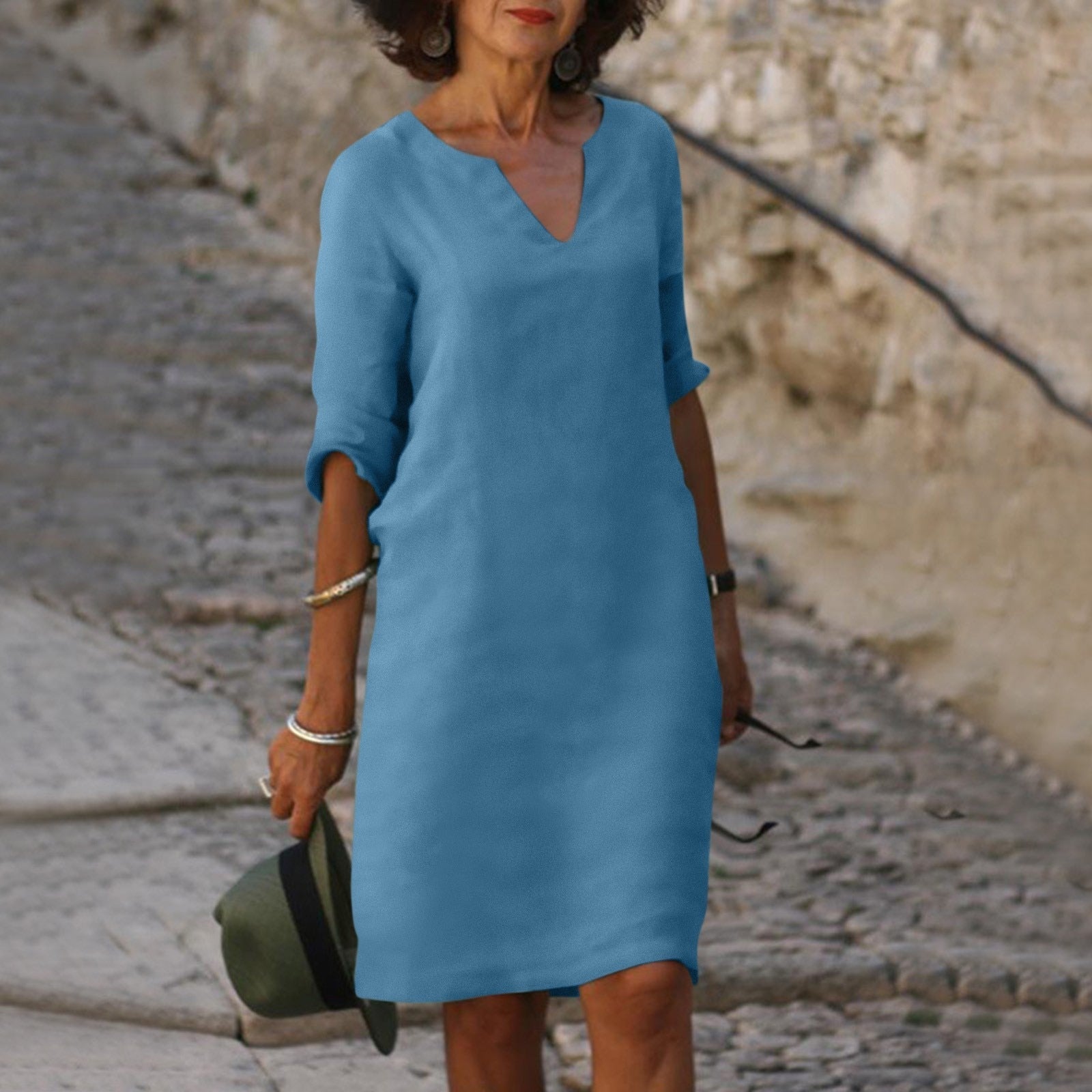 Abito estivo donna blu, maniche a tre quarti, scollo a V, indossato all'aperto su strada acciottolata. Elegante e casual.