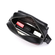 Borsa a tracolla in pelle nera aperta, mostra interno con rossetto, smartphone, portafoglio e fazzoletti. Accessorio moda elegante e pratico.