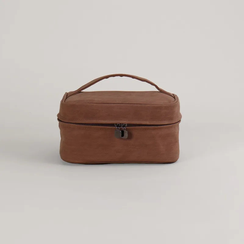 Astuccio da viaggio in pelle marrone con manico, chiusura a zip e doppio cursore. Elegante e pratico per organizzare accessori e cosmetici.