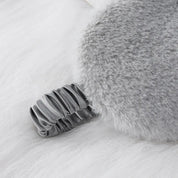 Cuscino grigio in pelliccia sintetica con manico elastico, design elegante e morbido, ideale per decorazione casa e comfort.