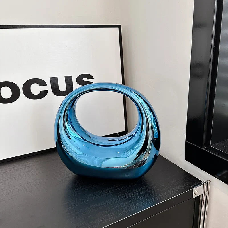 Vaso decorativo moderno in vetro blu lucido su mobile nero, design contemporaneo, accanto a un quadro con scritta "Focus". Arredamento elegante.