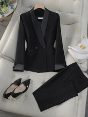 Completo donna elegante nero su divano beige, giacca con revers satinati, pantaloni abbinati, scarpe nere a punta, borsa bianca. Moda formale.
