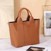 Borsa a mano in pelle marrone su sfondo chiaro, design elegante e moderno, ideale per moda femminile, accessorio di tendenza per ogni occasione.