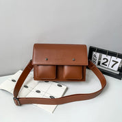 Borsa a tracolla in pelle marrone con due tasche frontali, design elegante e moderno, perfetta per l'uso quotidiano. Accessorio moda autunno.