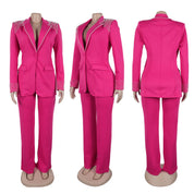 Completo donna elegante fucsia, giacca con dettagli brillanti su spalle e polsini, pantaloni abbinati. Moda femminile, abbigliamento formale.