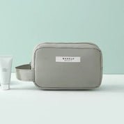 Astuccio da trucco grigio con cerniera, design minimalista, ideale per cosmetici e accessori da viaggio. Elegante e pratico per l'organizzazione.