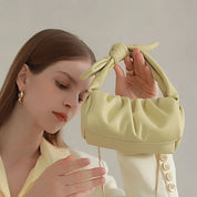 Donna con borsa a mano verde chiaro, design moderno, nodo decorativo, abbigliamento elegante, moda femminile, accessorio di tendenza.