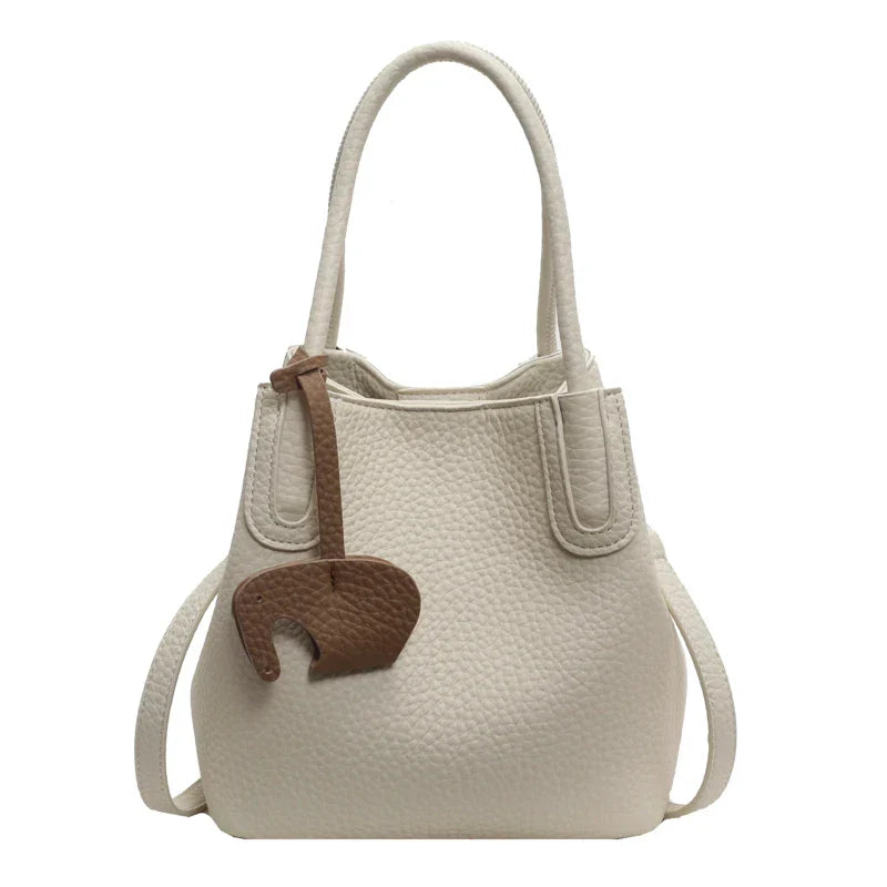 Borsa a mano in pelle bianca con texture, decorazione marrone a forma di elefante, manici doppi, design elegante. Accessorio moda donna.