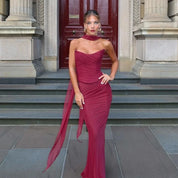 Abito da sera elegante rosso bordeaux, lungo e aderente, con sciarpa abbinata, indossato da modella su gradini di edificio storico.