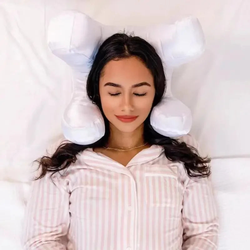 Donna che dorme su cuscino ergonomico bianco a forma di osso, indossa pigiama a righe rosa. Comfort, supporto cervicale, riposo notturno.