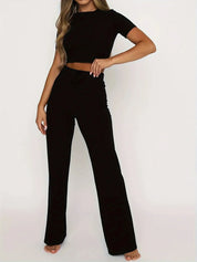 Donna in completo nero elegante, top corto e pantaloni a vita alta. Abbigliamento moda donna, stile casual chic, perfetto per ogni occasione.
