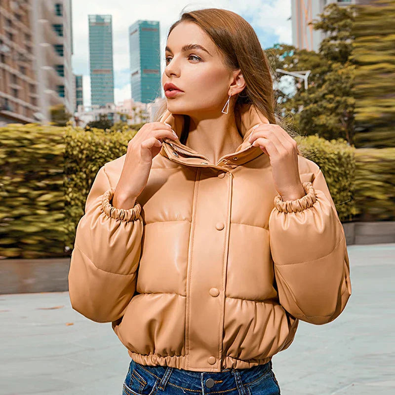 Giacca imbottita donna beige, moda autunno, chiusura a bottoni, colletto alto, sfondo urbano. Elegante e calda, perfetta per città.
