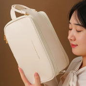 Donna con borsa cosmetica bianca, elegante e spaziosa, con cerniera dorata. Ideale per viaggi, organizzazione trucco e accessori.