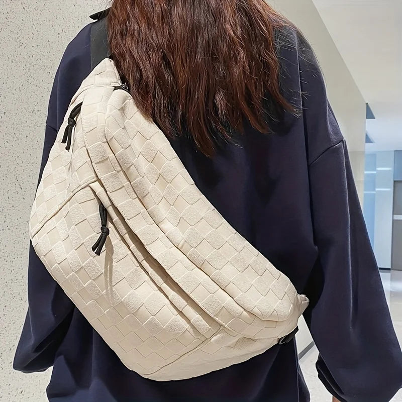 Zaino a tracolla beige intrecciato su donna con maglia blu, design moderno e spazioso, ideale per moda urbana e viaggi.