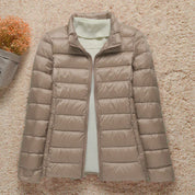 Giacca piumino beige da donna su sfondo chiaro, con maglione bianco a collo alto. Moda invernale, abbigliamento caldo e casual.