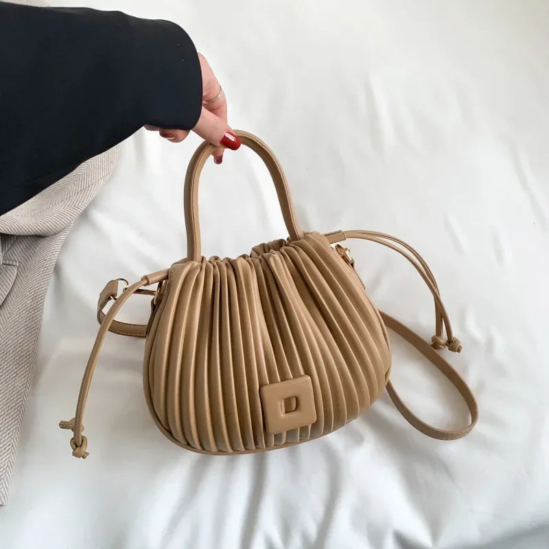 Borsa a mano beige in pelle plissettata con manici arrotondati e tracolla regolabile, design elegante e moderno, accessorio moda donna.