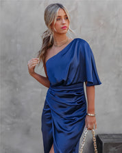 Abito elegante blu in raso monospalla, donna con capelli biondi raccolti, accessori oro, sfondo neutro. Moda femminile, abbigliamento da sera.