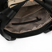 Interno di una borsa nera con fodera a righe bianche e nere, tasca con cerniera. Design elegante, ideale per moda donna e accessori.