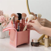 Set di pennelli trucco in custodia rosa su tavolo da toeletta con specchio, fiori e cosmetici. Accessori bellezza, organizzazione trucco elegante.