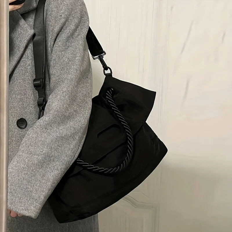 Cappotto grigio con borsa a tracolla nera in tessuto, design elegante e moderno, ideale per moda autunno inverno. Accessorio versatile e chic.