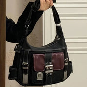 Borsa a tracolla nera con dettagli in metallo, tasca frontale bordeaux, fibbie decorative e chiusura a zip. Design elegante e moderno.