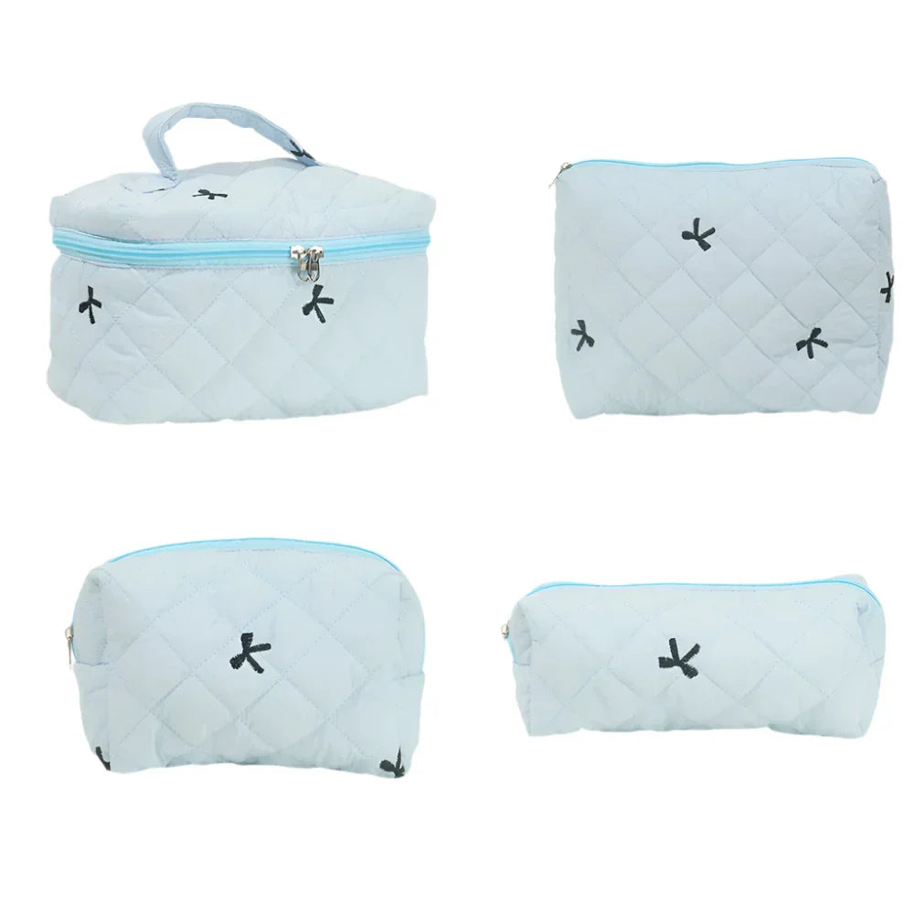 Set di quattro borse da viaggio trapuntate azzurre con cerniera, motivi neri. Include borsa grande con manico, pochette, astuccio e borsa media.
