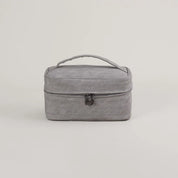 Borsa da viaggio grigia con manico, design compatto e chiusura a zip. Ideale per organizzare accessori e cosmetici. Elegante e funzionale.