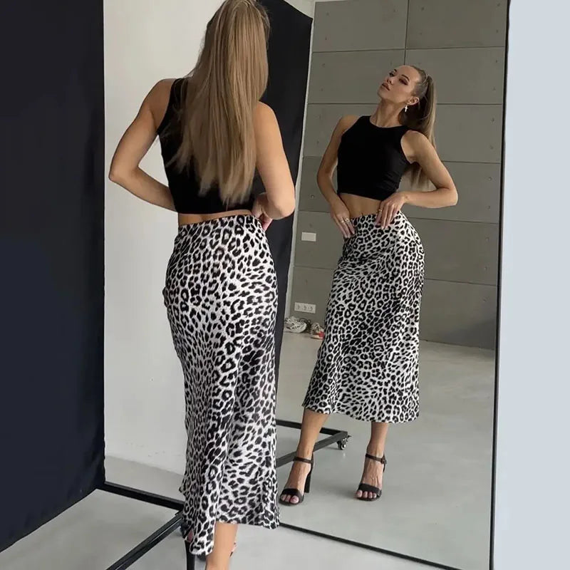 Donna con top nero e gonna leopardata, specchio, moda elegante, abbigliamento casual, look moderno, scarpe con tacco, capelli lunghi.