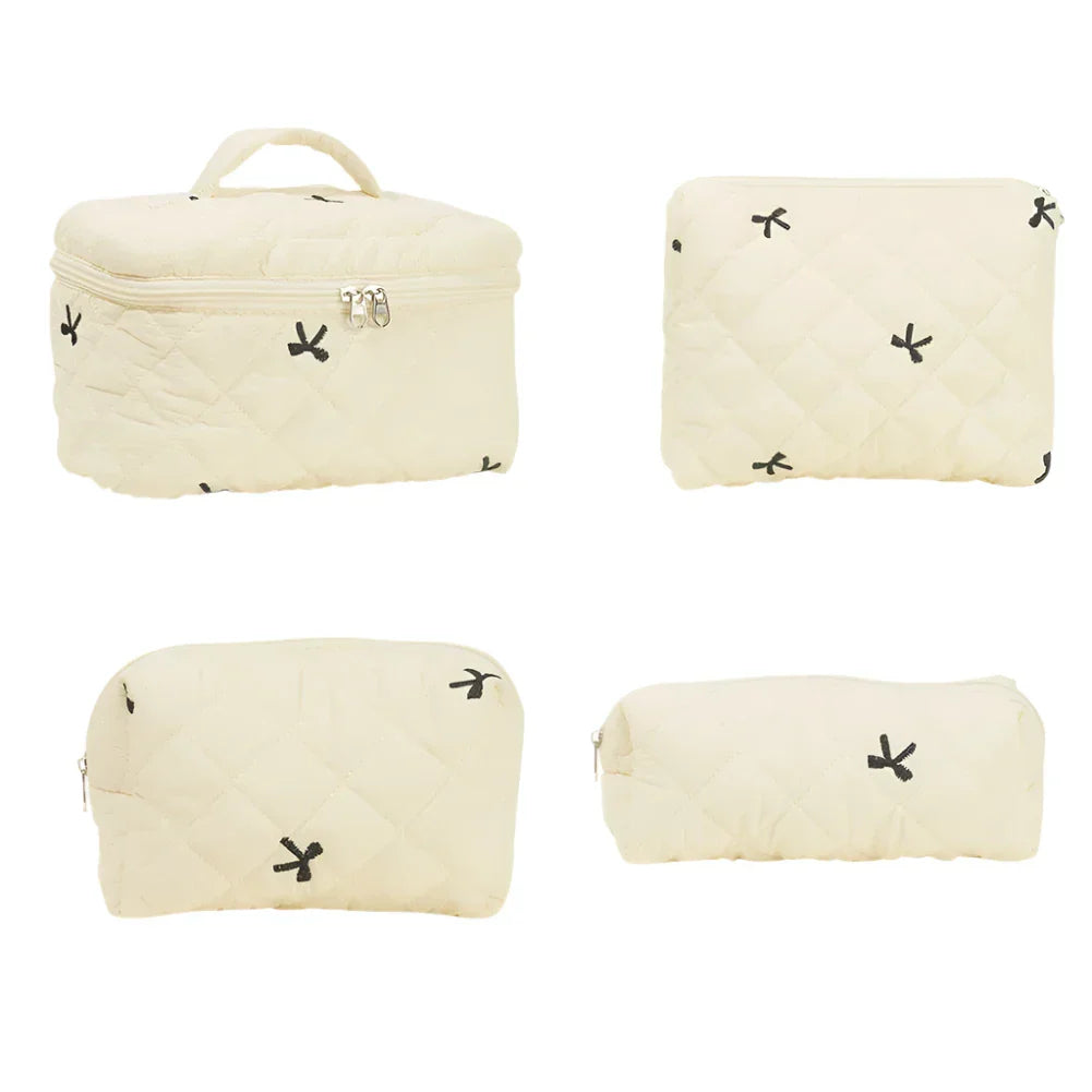 Set di quattro borse da viaggio beige trapuntate con cerniera, design minimalista con piccoli motivi neri. Ideale per organizzare cosmetici e accessori.
