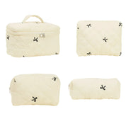 Set di quattro borse da viaggio beige trapuntate con cerniera, design minimalista con piccoli motivi neri. Ideale per organizzare cosmetici e accessori.