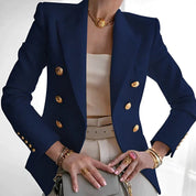 Giacca blazer blu scuro da donna, doppiopetto con bottoni dorati, abbinata a top bianco e accessori oro. Elegante moda femminile.
