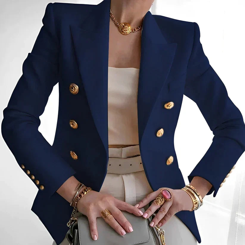 Giacca blazer blu scuro da donna, doppiopetto con bottoni dorati, abbinata a top bianco e accessori oro. Elegante moda femminile.