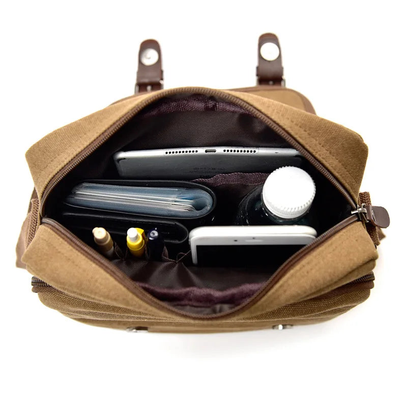 Zaino in tela marrone aperto, contenente tablet, smartphone, bottiglia d'acqua, astuccio e penne. Accessori organizzati per viaggio e lavoro.