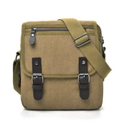 Borsa a tracolla in tela marrone con fibbie in pelle, tasca frontale con zip, design unisex, ideale per viaggi e uso quotidiano.