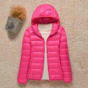 Giacca invernale rosa con cappuccio, imbottita, su sfondo beige. Moda donna, abbigliamento caldo, stile casual. Perfetta per l'inverno.