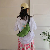 Zaino a forma di pisello verde su ragazza con cappello giallo, maglietta bianca e gonna rosa con fragole. Accessorio moda casual e originale.