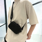 Borsa a tracolla nera unisex, design moderno e compatto, indossata su maglietta beige. Accessorio moda casual, ideale per ogni occasione.