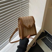 Borsa a tracolla marrone chiaro con motivo a rombi, chiusura a bottone, accanto a laptop su scrivania. Accessorio moda elegante e pratico.