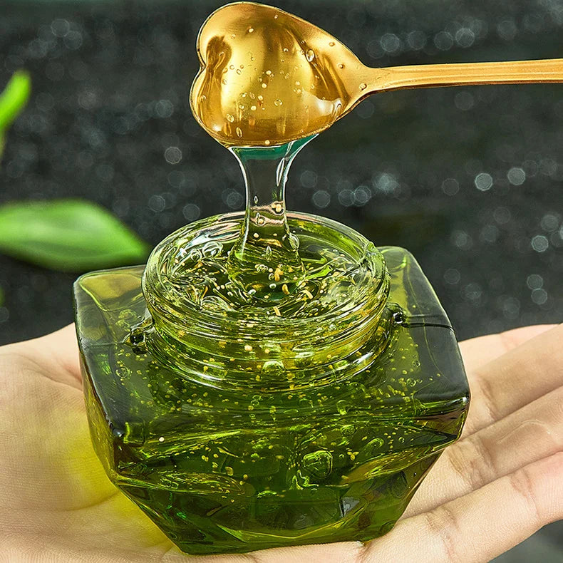 Barattolo di vetro verde con gel trasparente, cucchiaio dorato a forma di cuore. Cosmetico idratante naturale, cura della pelle, bellezza.