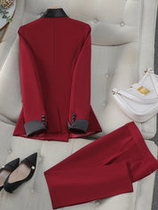 Completo elegante rosso da donna su divano beige, con giacca e pantaloni abbinati. Accessori: borsa bianca e scarpe nere con tacco.