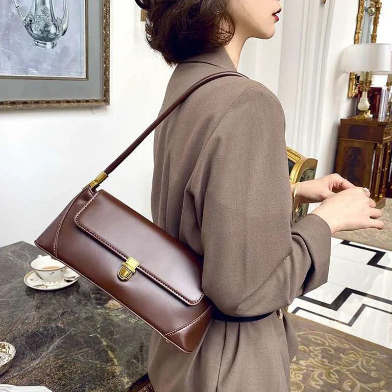 Donna con borsa a tracolla marrone in pelle, elegante e moderna, in un ambiente lussuoso. Accessorio moda femminile, stile sofisticato.