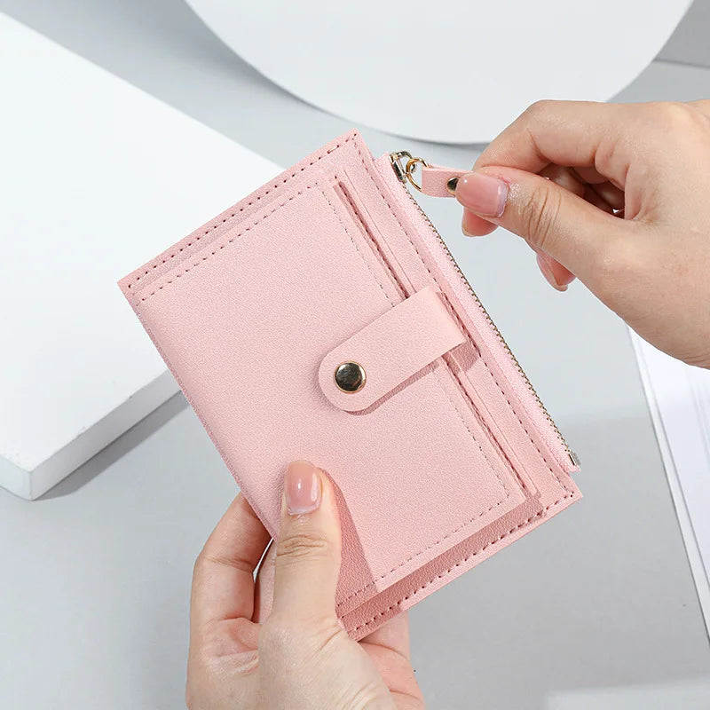 Portafoglio rosa in pelle sintetica con chiusura a bottone e zip, design compatto, ideale per donna. Accessorio moda elegante e pratico.