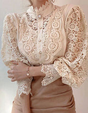 Blusa in pizzo beige con maniche a sbuffo, dettagli floreali e bottoni decorativi. Elegante e raffinata, ideale per moda femminile e abbigliamento chic.