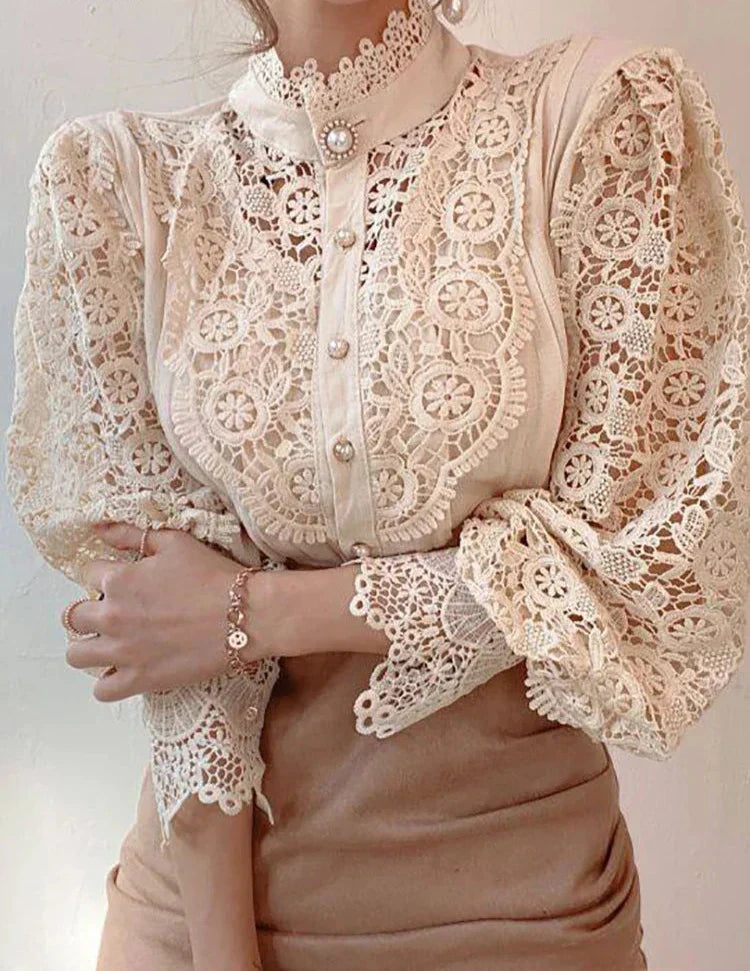 Blusa in pizzo beige con maniche a sbuffo, dettagli floreali e bottoni decorativi. Elegante e raffinata, ideale per moda femminile e abbigliamento chic.