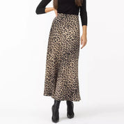 Gonna lunga a vita alta con stampa leopardata, indossata con maglia nera a maniche lunghe e stivali neri. Moda donna, abbigliamento casual elegante.