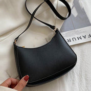 Borsa a tracolla nera in pelle sintetica su sfondo bianco, design minimalista, elegante e versatile, perfetta per moda femminile e uso quotidiano.