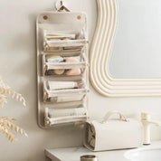 Organizer da bagno appeso con tasche trasparenti, contenente cosmetici e accessori. Design elegante, ideale per organizzare il bagno.