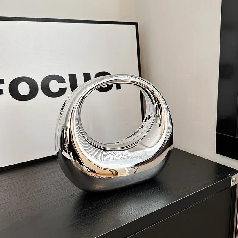 Scultura moderna in metallo cromato su mobile nero, design astratto, decorazione d'interni elegante, riflessi lucidi, arte contemporanea.