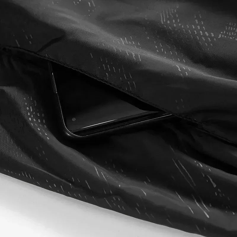 Giacca impermeabile nera con tasca nascosta, design moderno, tessuto resistente, ideale per smartphone, abbigliamento outdoor, moda funzionale.