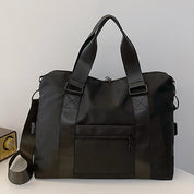 Borsa da viaggio nera in nylon impermeabile con manici robusti e tracolla regolabile, tasca frontale con zip, ideale per viaggi e palestra.